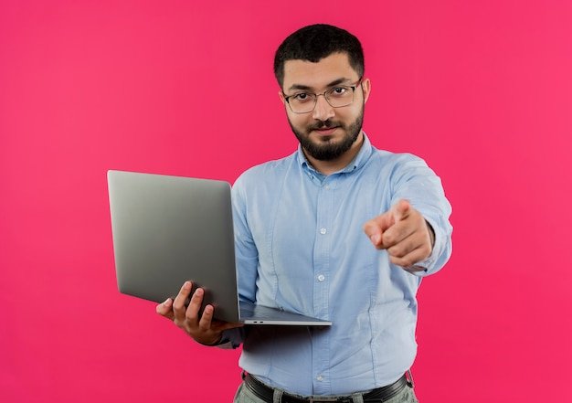 Man pointing with laptop on pink